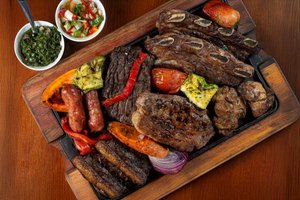 Traditionelles argentinisches Asado mit verschiedenen Fleischspezialitäten und gegrilltem Gemüse
