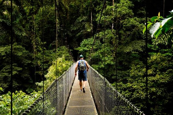 Wanderer auf einer Hängebrücke im tropischen Regenwald der Arenal-Region in Costa Rica