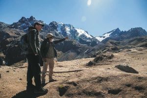 Zwei Wanderer genießen den Ausblick auf die Andenlandschaft während einer Wanderung zum Rainbow Mountain bei Cusco in Peru.